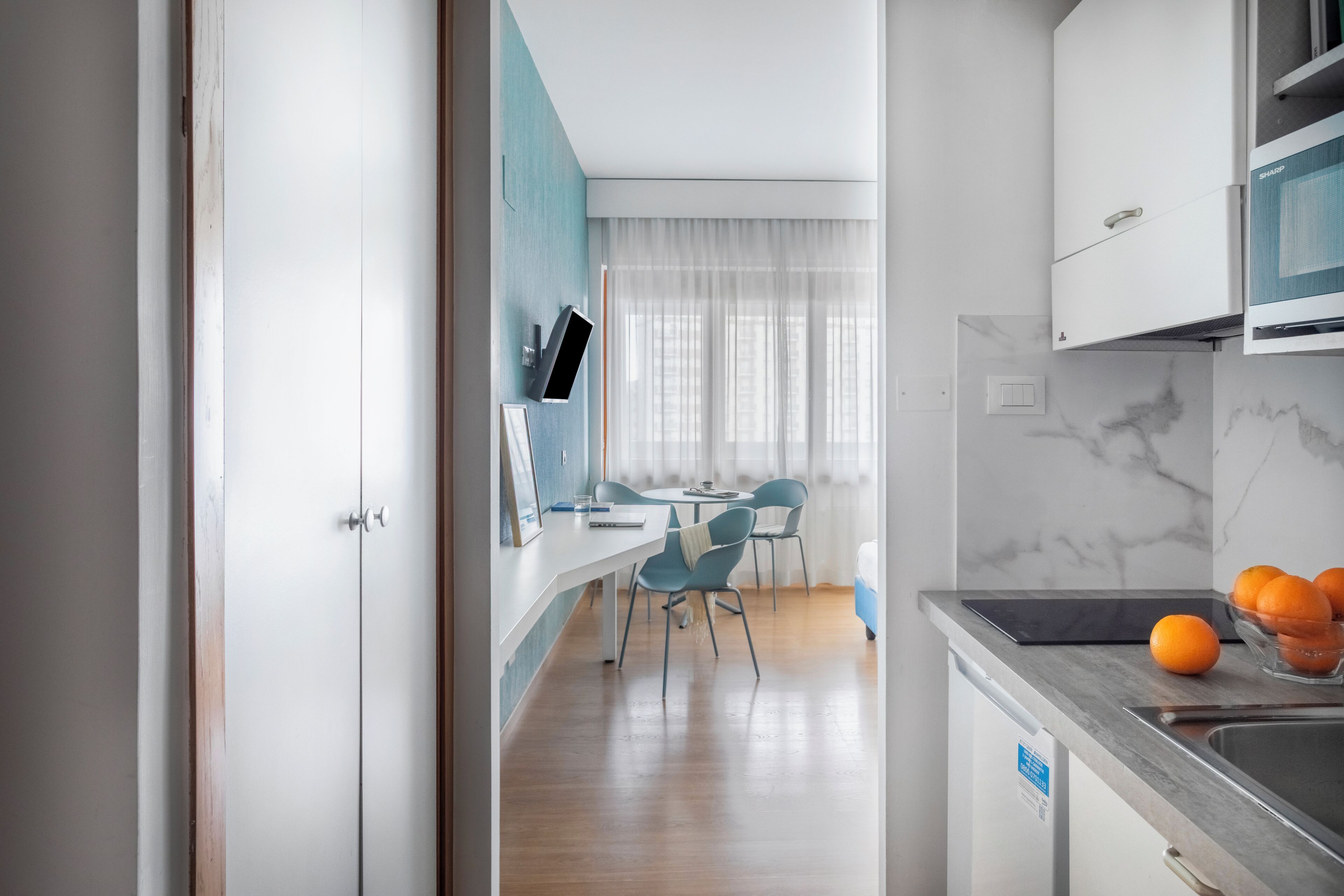 A modern kitchen with a marble countertop, a sink, and a dining area with chairs and a table.