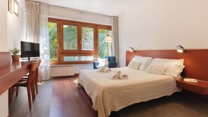 A hotel room with a bed, a desk with a TV, a chair, a lamp, and a window with curtains. - Marbela Apartments & Suites (Palermo)
