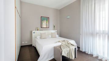 Un dormitorio con una cama, una mesita de noche y un cuadro en la pared, además de una ventana con cortinas.