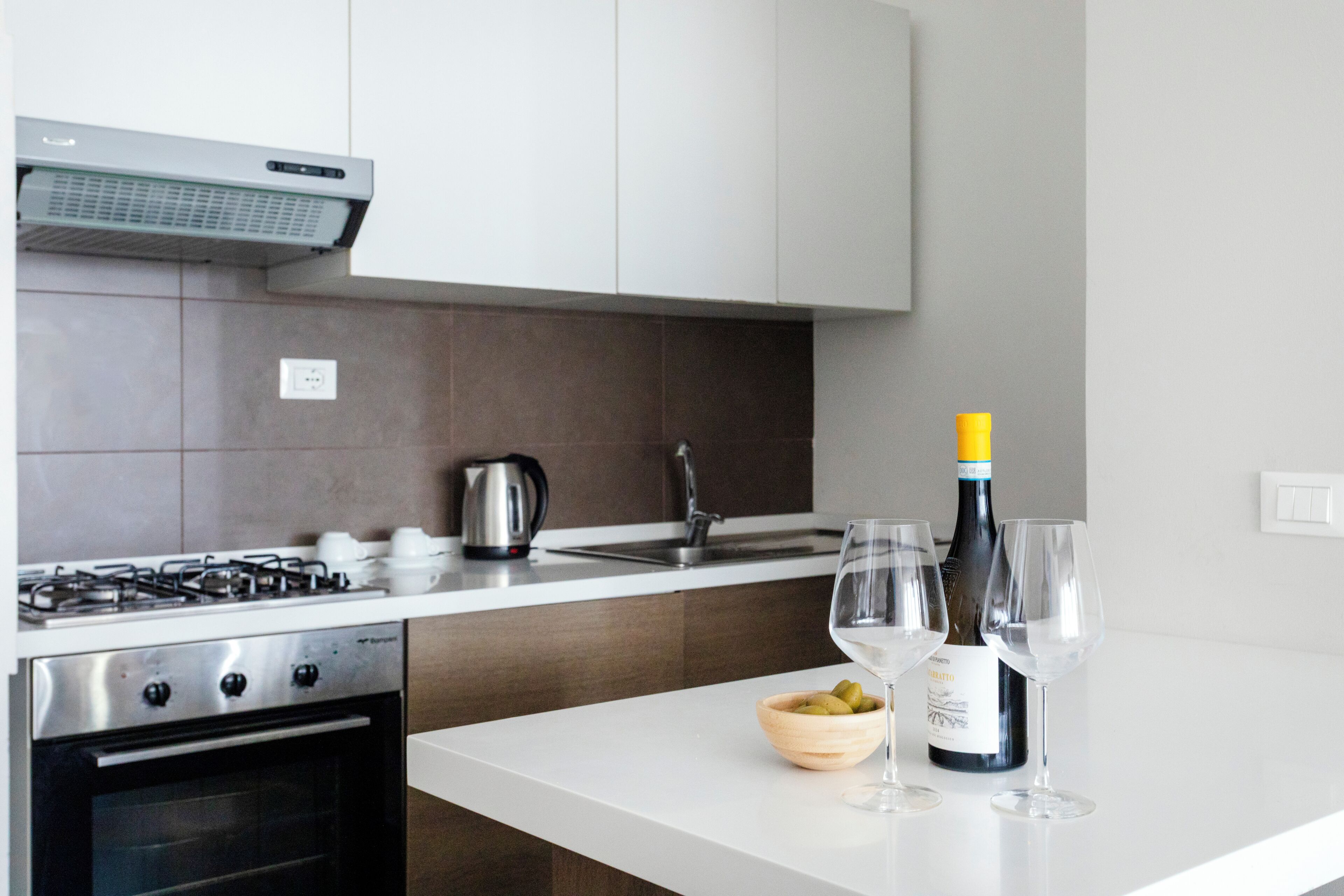 Une cuisine moderne équipée d’une cuisinière à gaz, d’un four et d’un plan de travail blanc.