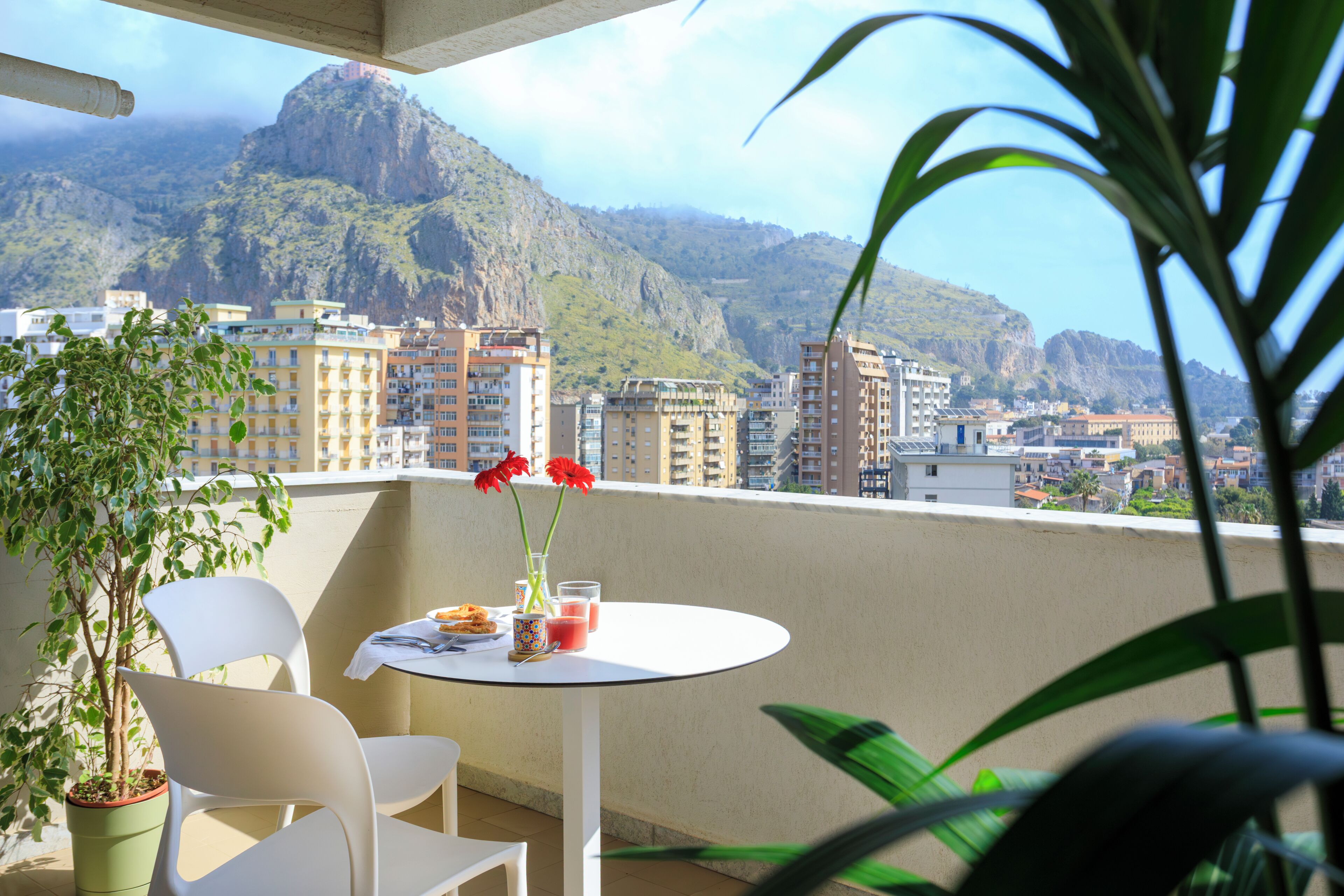 Ein Balkon mit Tisch, Stühlen, einer Topfpflanze und Blick auf eine Berglandschaft.
