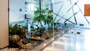 A modern indoor space with a glass partition, a water feature, and various plants. - Marbela Apartments & Suites (Palermo)
