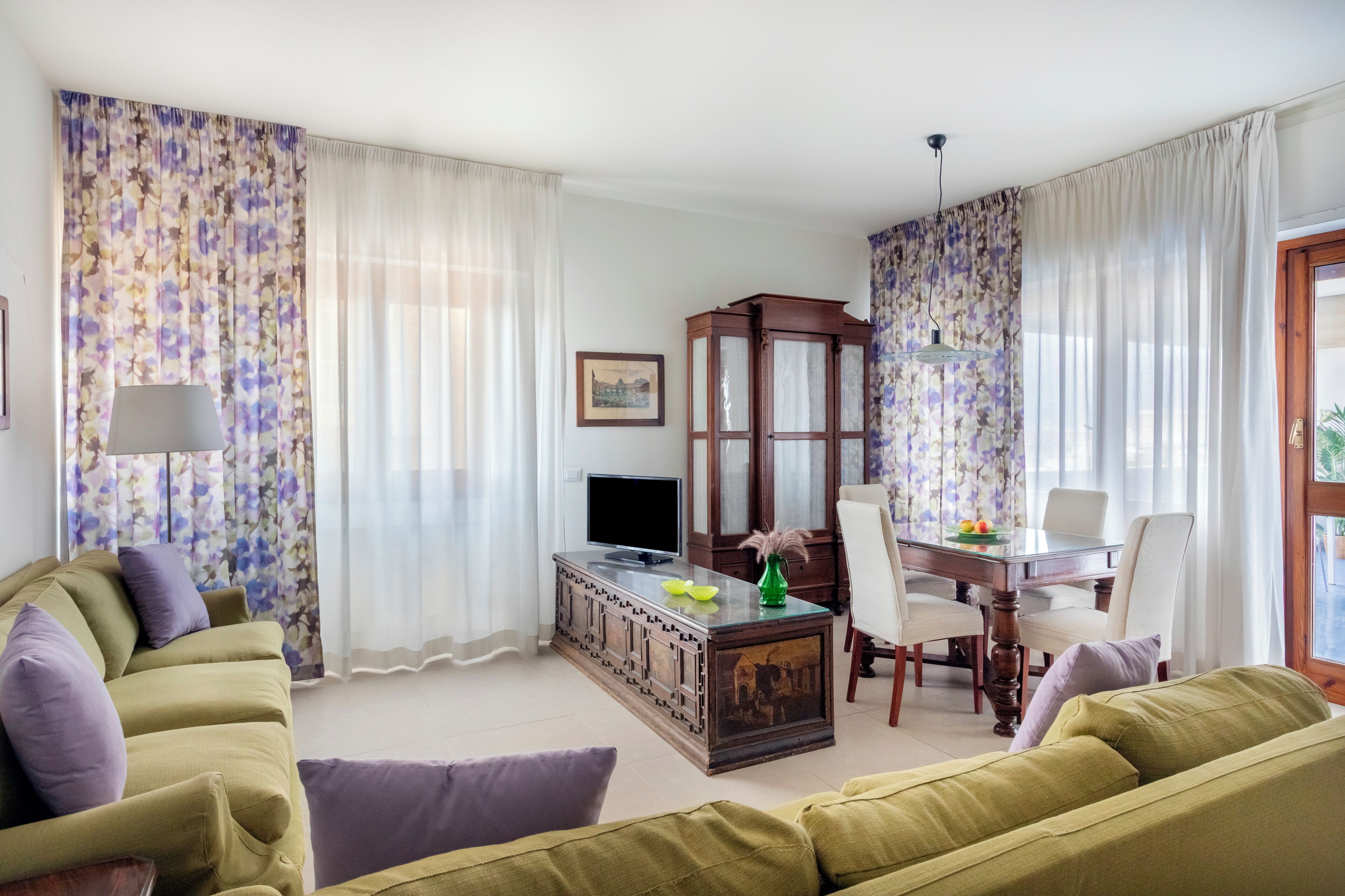 Una sala de estar con sofá, televisor, mueble bajo y comedor con sillas y mesa.