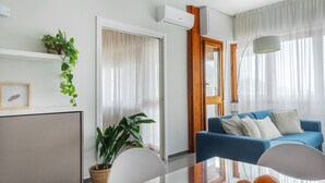 A modern living room with a blue sofa, a dining table, and a potted plant. - Marbela Apartments & Suites (Palermo)