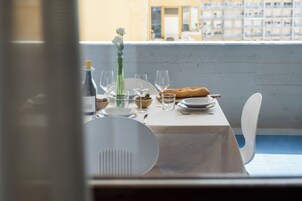 A dining table set with plates, glasses, a bottle, a vase with flowers, and a baguette.