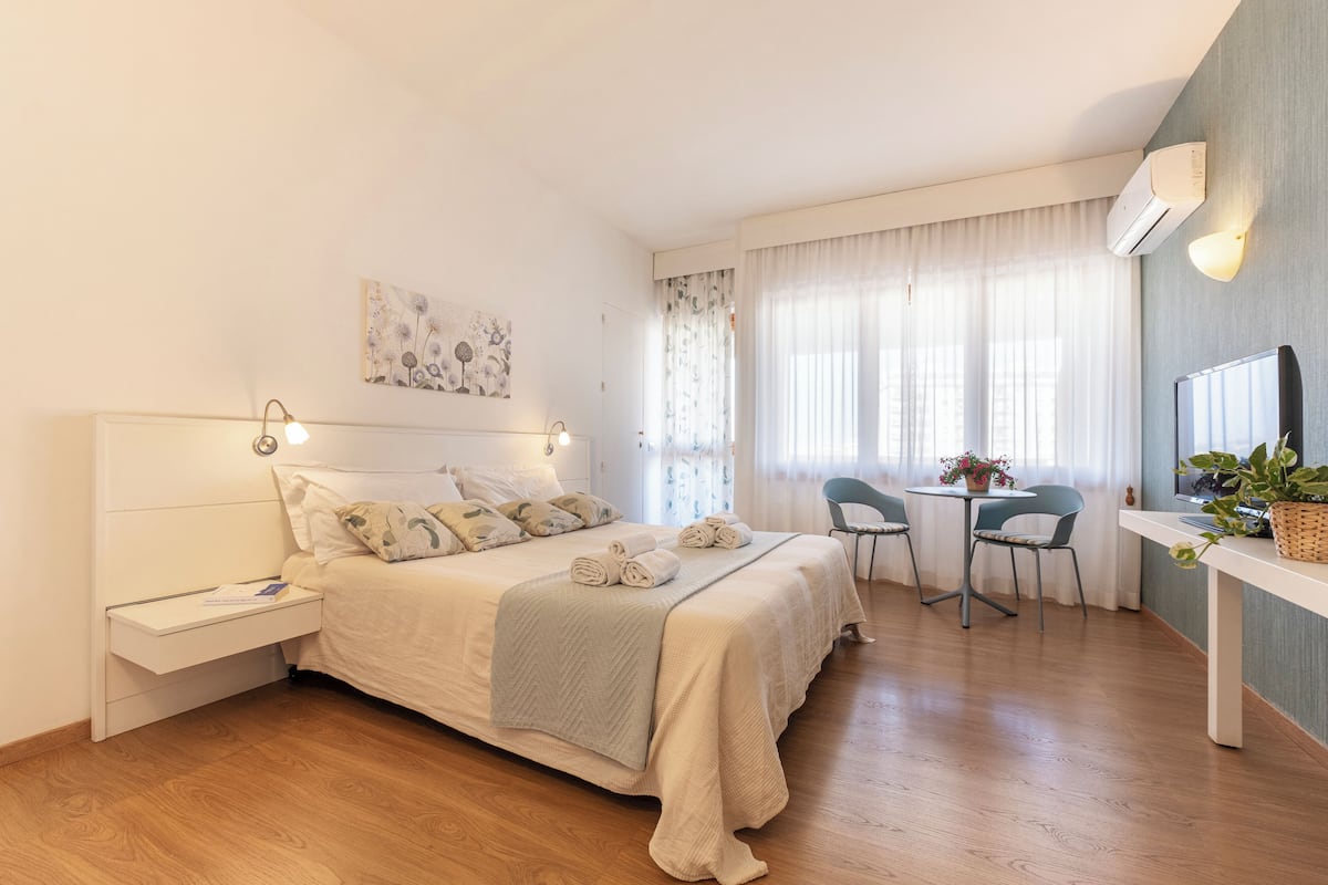 A modern bedroom with a bed, bedside tables, a desk, and a chair.