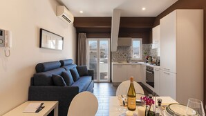 A modern living room with a sofa, a dining table with wine glasses and a bottle, and a kitchen in the background. - Marbela Apartments & Suites (Palermo)