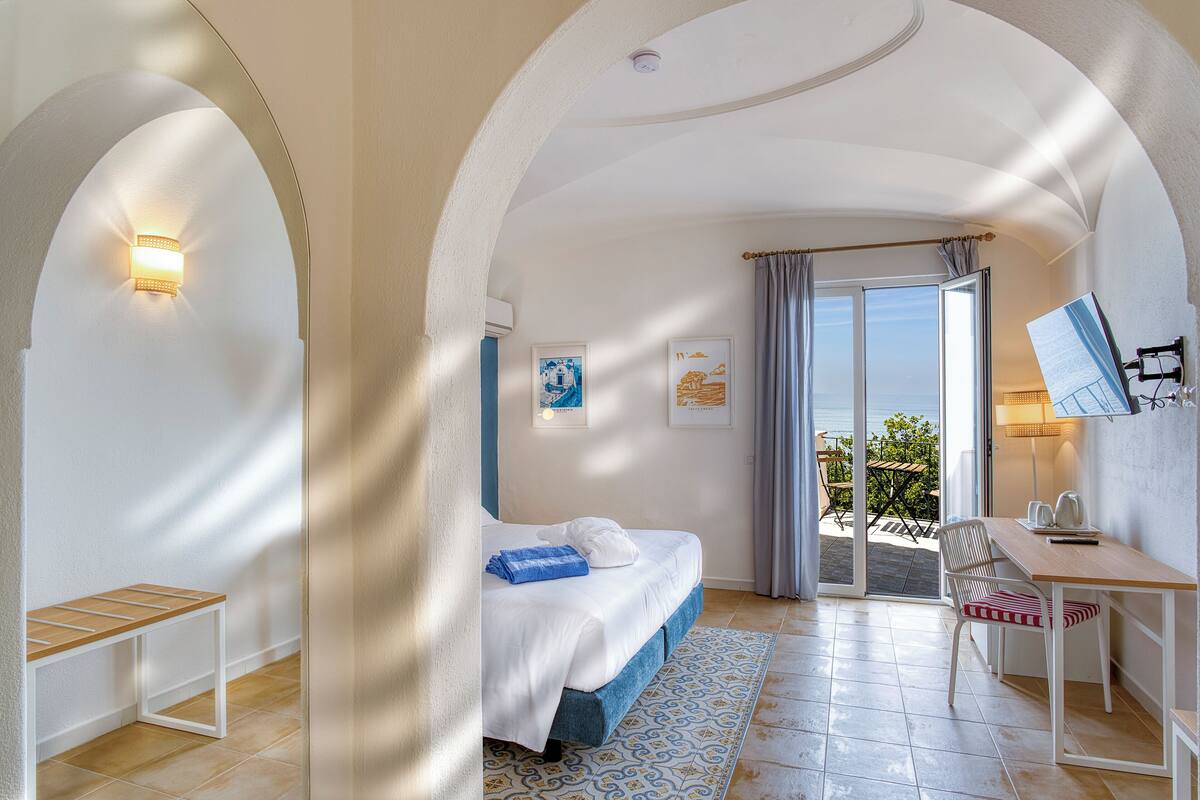 Un dormitorio con cama, escritorio, silla y vistas al exterior.