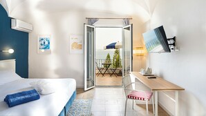 Une chambre d’hôtel comprenant un lit, un bureau, une chaise, une télévision et un balcon avec une table et des chaises.