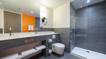 A modern bathroom with a large mirror, a shower enclosure, and a vanity with a towel rack.
