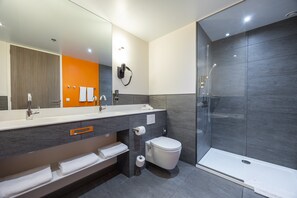 Een moderne badkamer met een grote spiegel, een douchecabine en een wastafel met een handdoekhouder.