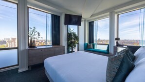 Een hotelkamer met een groot bed, een bureau, een televisie en uitzicht op de stad.