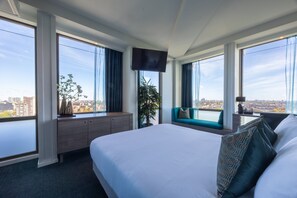 Una habitación de hotel con una cama grande, un escritorio, un televisor y vistas a la ciudad.