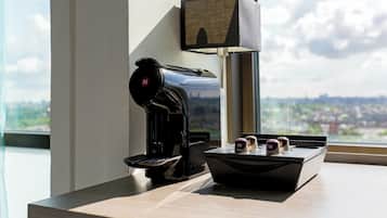 A coffee machine, a lamp, and a tray with two cups on a counter by a window.