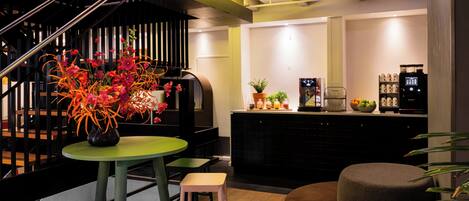Un interior moderno con una escalera, una mesa verde con un florero, una zona de cocina con electrodomésticos y un espacio de estar.