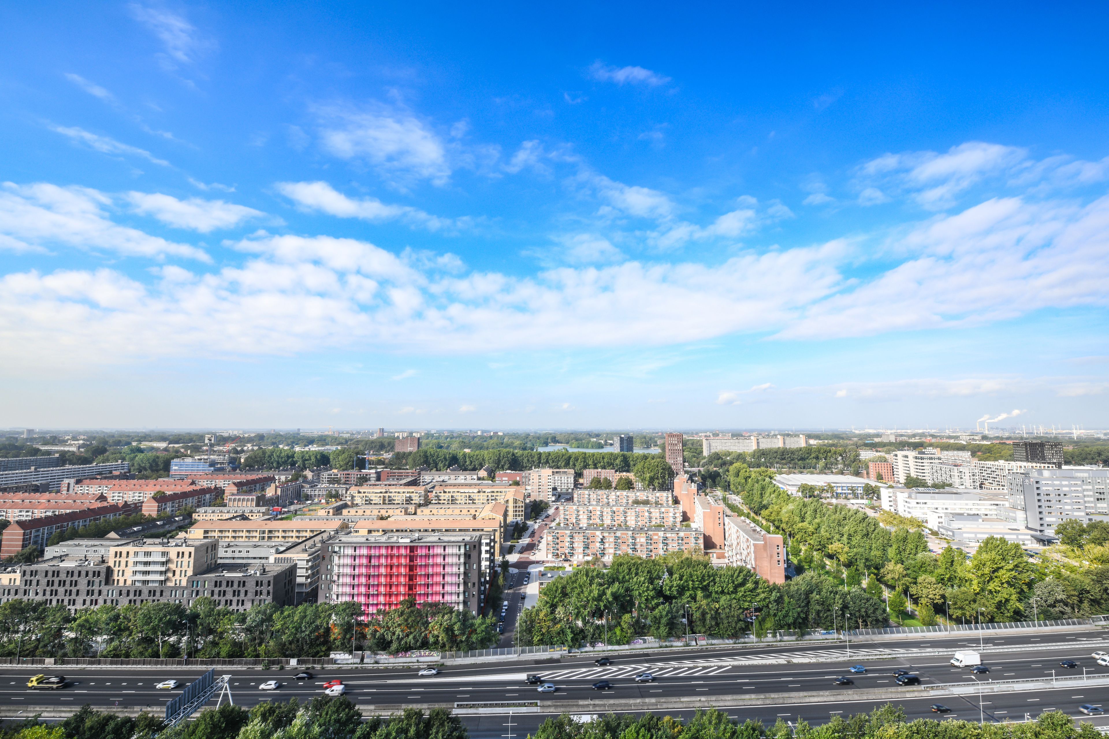 Een stadsbeeld met een brede weg, meerdere gebouwen en een heldere lucht.