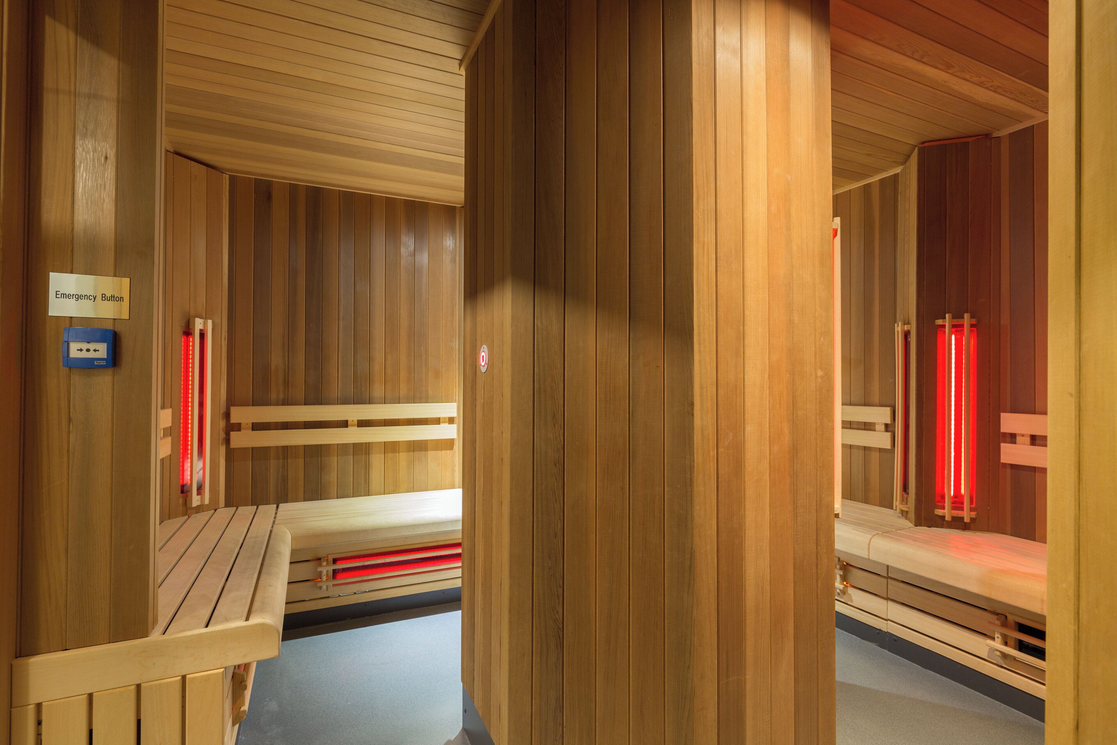 Eine Sauna mit Holzbänken und einem Schild, das einen Notrufknopf kennzeichnet.