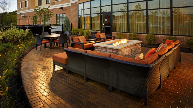 An outdoor patio with a fire pit, seating area, and a TV screen. - Courtyard by Marriott Pittsburgh Washington/Meadow Lands (Washington)