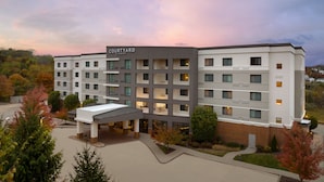 A Courtyard by Marriott hotel with a modern design, featuring multiple floors and a covered entrance. - Courtyard by Marriott Pittsburgh Washington/Meadow Lands (Washington)