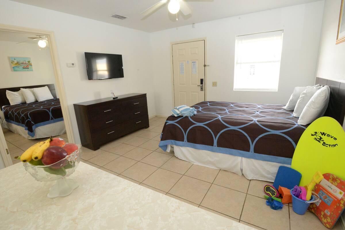 A bedroom with a bed, a dresser, a television, and a window.