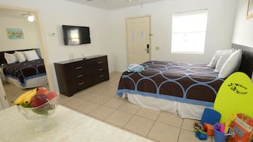 A bedroom with a bed, a dresser, a television, and a window.