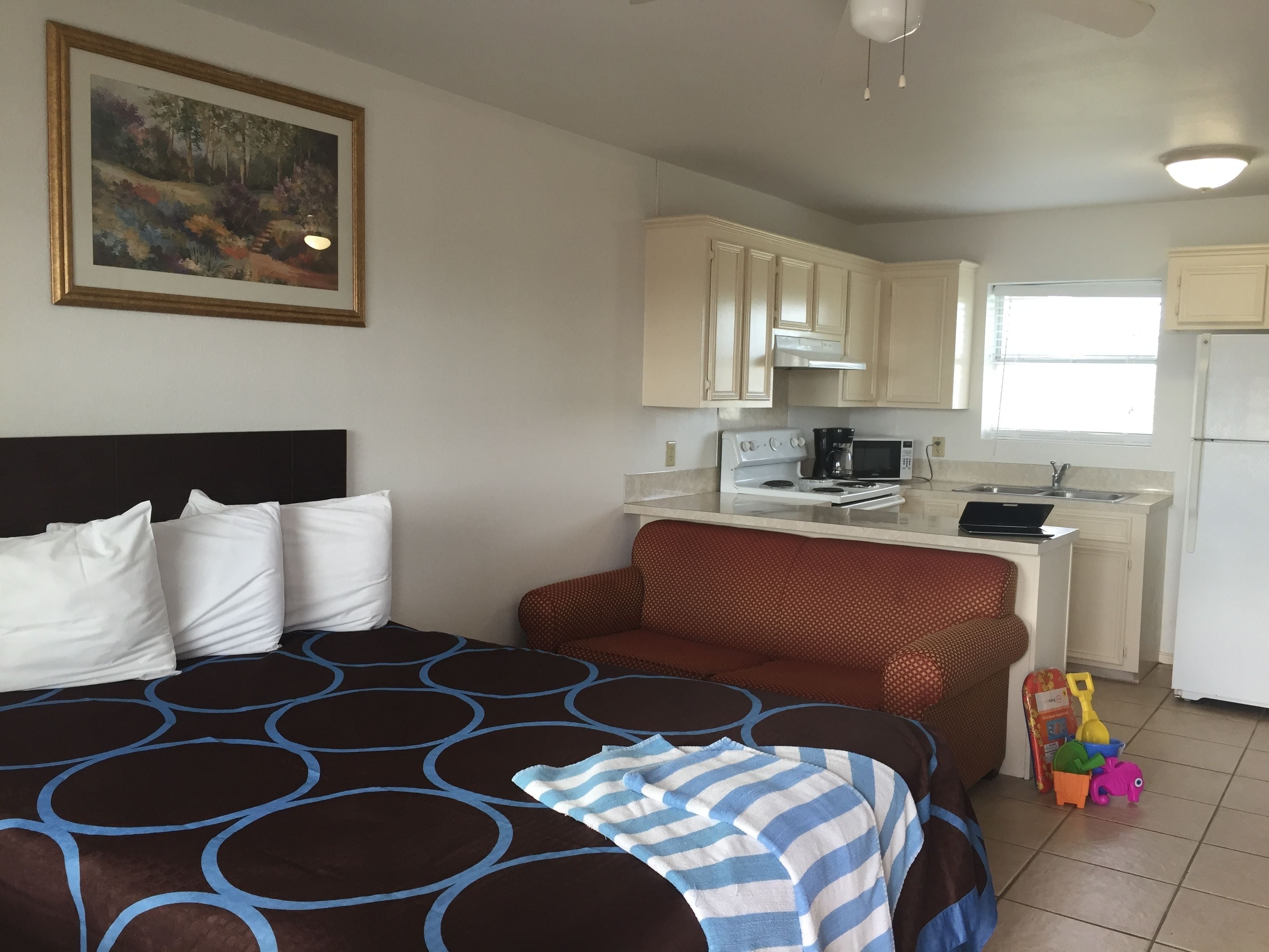 Una habitación de hotel con una cama, kitchenette y una pequeña zona de juegos.