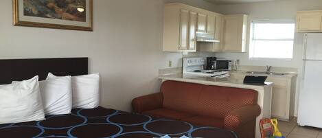 Una habitación de hotel con una cama, kitchenette y una pequeña zona de juegos.