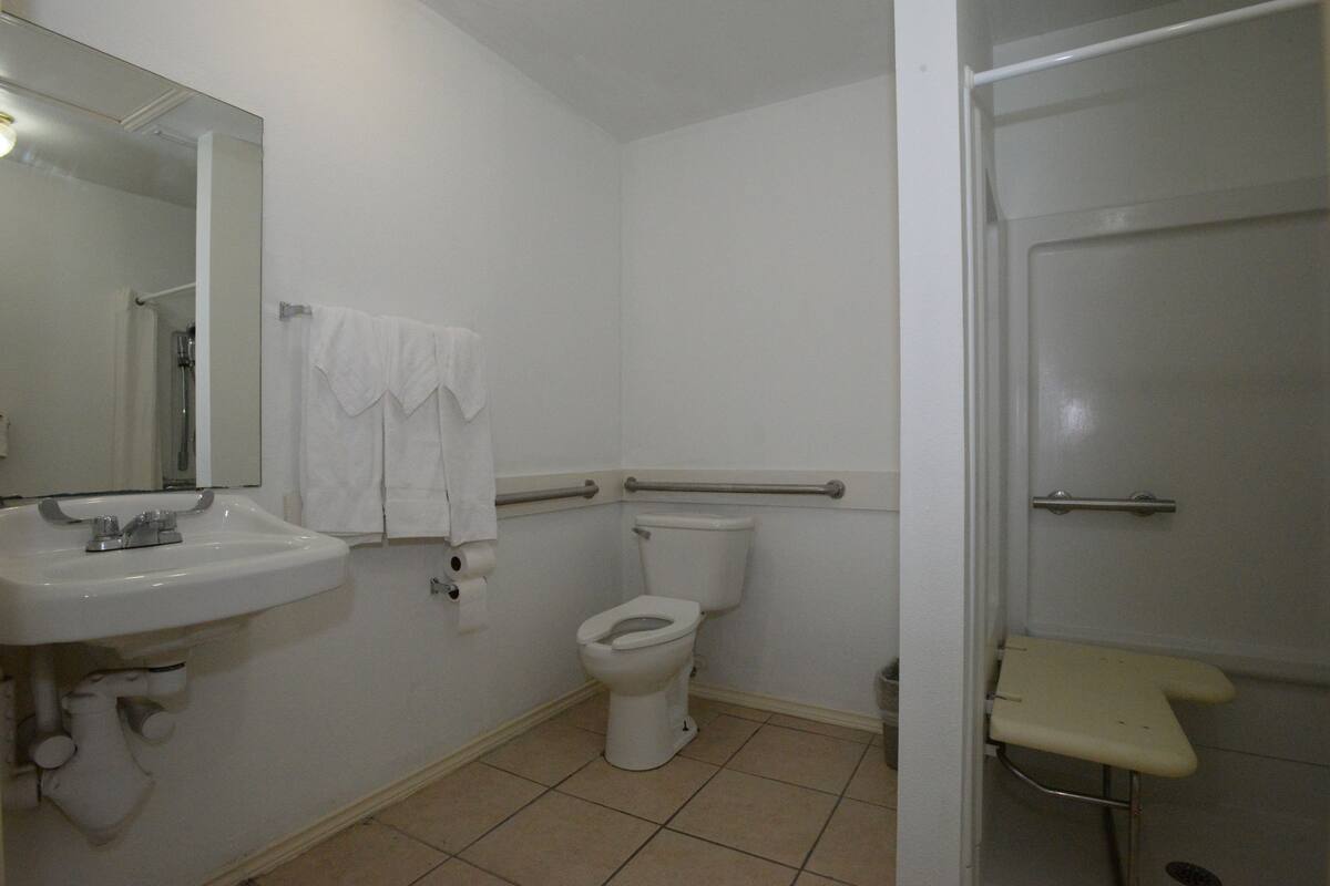 A bathroom with a white sink, toilet, and shower area.