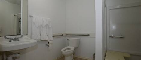 Un baño con lavamanos, inodoro y zona de ducha blancos.