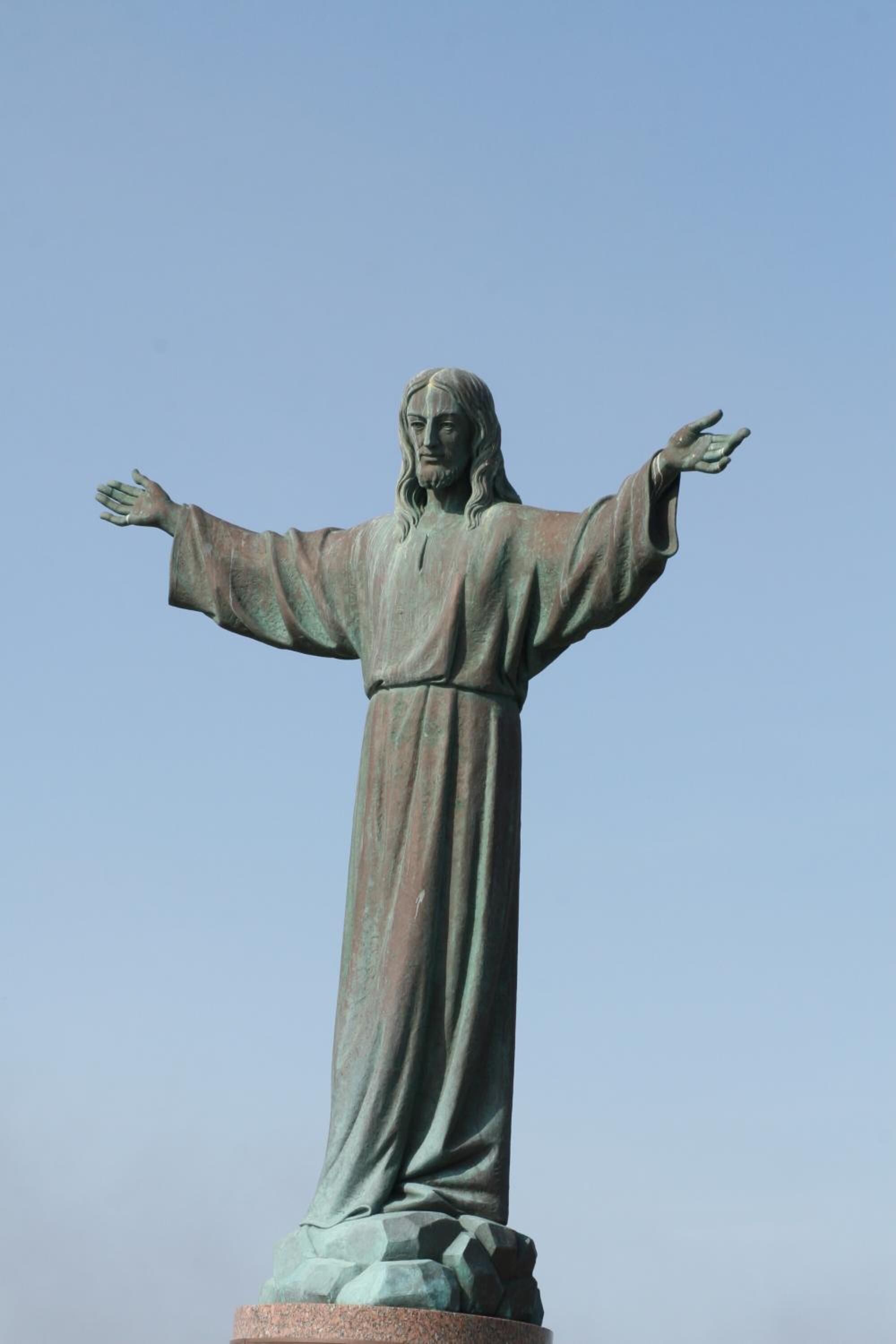 A statue with outstretched arms, standing on a pedestal.