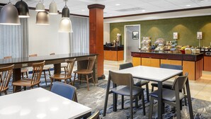 A hotel dining area with multiple tables and chairs, a coffee station, and a counter with food items. - Fairfield Inn & Suites by Marriott Paducah (Paducah)