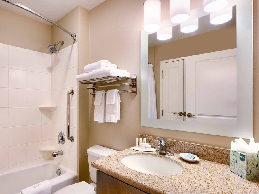 A bathroom with a bathtub, a sink with a mirror, and a towel rack.