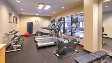 A gym with treadmills, elliptical machines, and weight benches.