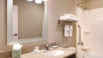 A bathroom with a sink, mirror, towel rack, and a shower area.