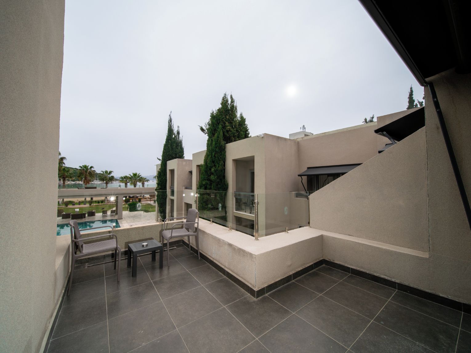 A rooftop terrace with a pool, seating area, and a view of the surrounding landscape.