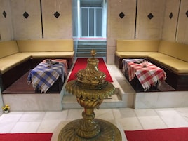 Eine Hotelhalle mit einer zentralen Fontäne, zwei Sofas und zwei Tischen mit karierten Tischdecken.