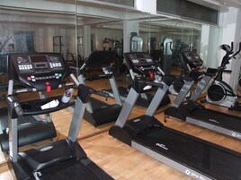 Academia com várias esteiras de corrida Pro Fitness, espelhos e equipamentos de ginástica.