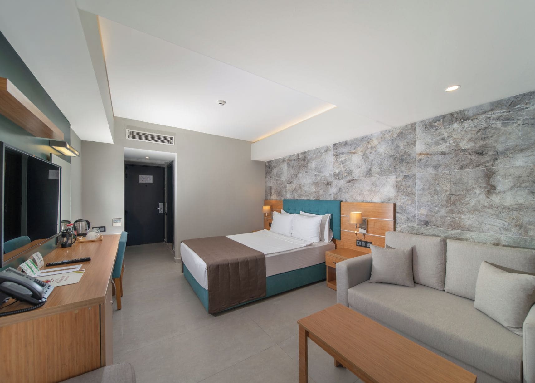 Una habitación de hotel moderna con una cama, un sofá, un escritorio y un televisor.