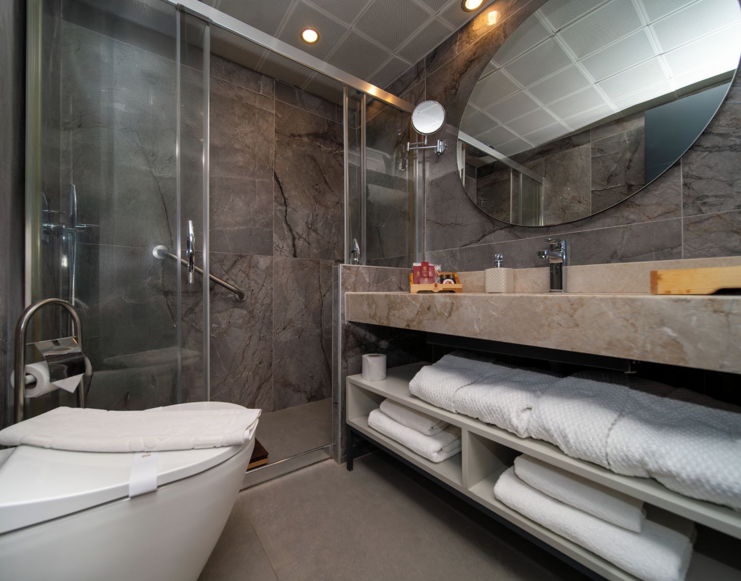 A modern bathroom with a glass-enclosed shower, a white bathtub, and a vanity with a mirror.
