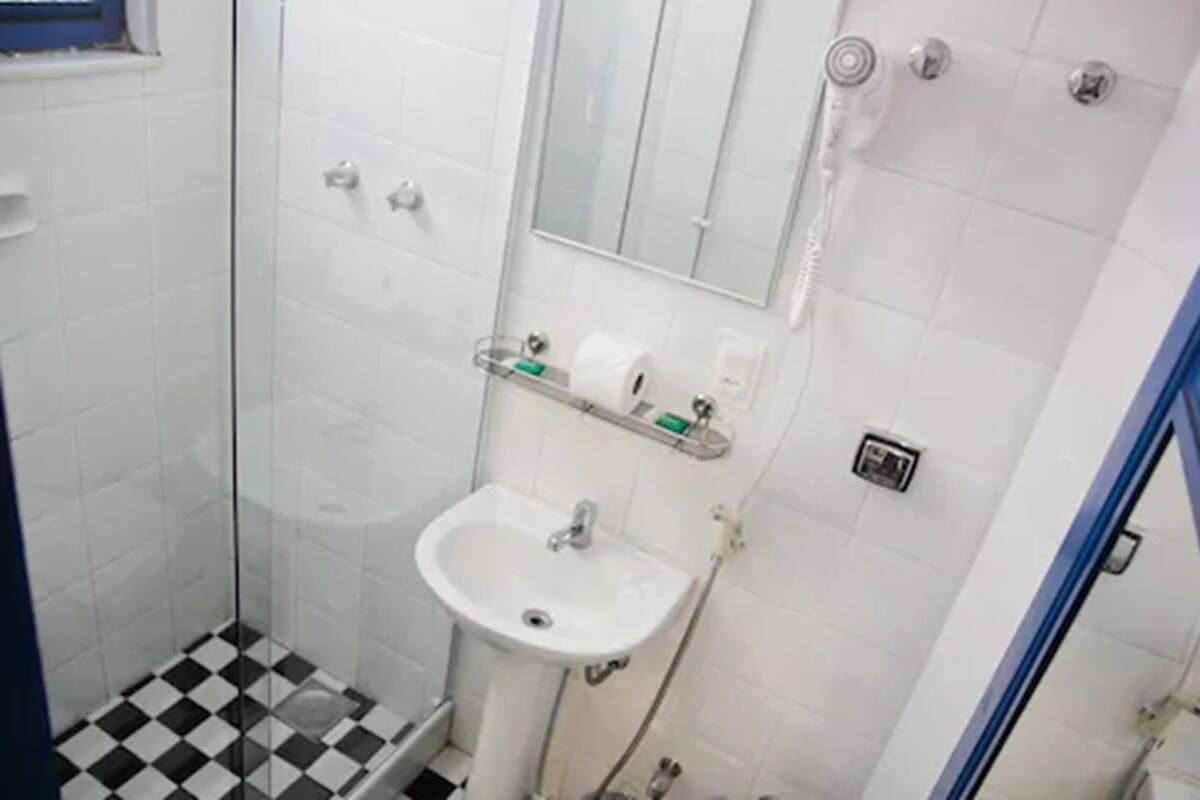 Un bany amb plat de dutxa de vidre, un lavabo blanc i un mirall sobre el lavabo.