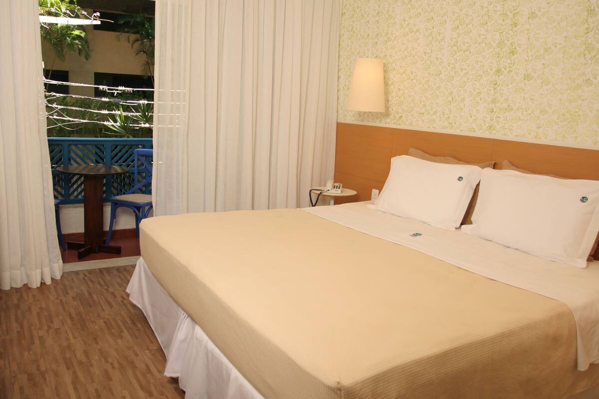 Una habitació d'hotel amb un llit gran, una taula petita i una cadira.