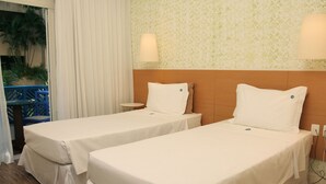 Dos camas individuales con ropa blanca en una habitación de hotel.