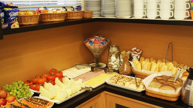 Un bufé con diversas opciones de comida, entre ellas frutas, quesos y panes.