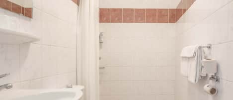 Un baño con lavamanos, inodoro, ducha y espejo.