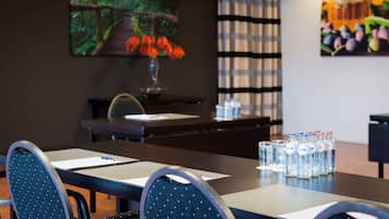 A conference room with a long table, chairs, a vase with flowers, water bottles, and artwork on the walls.
