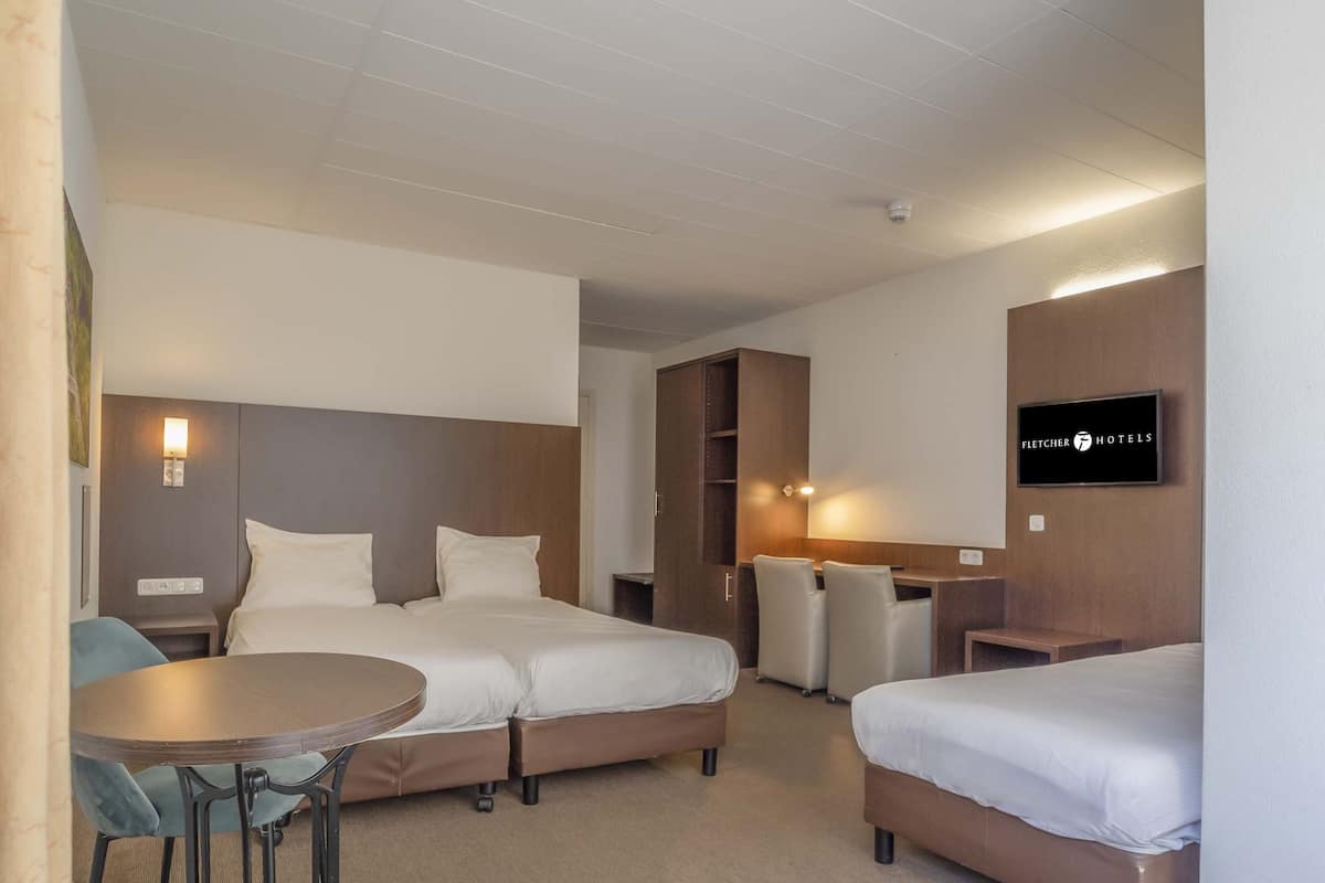 Une chambre d’hôtel avec deux lits, un bureau, une chaise et un téléviseur.