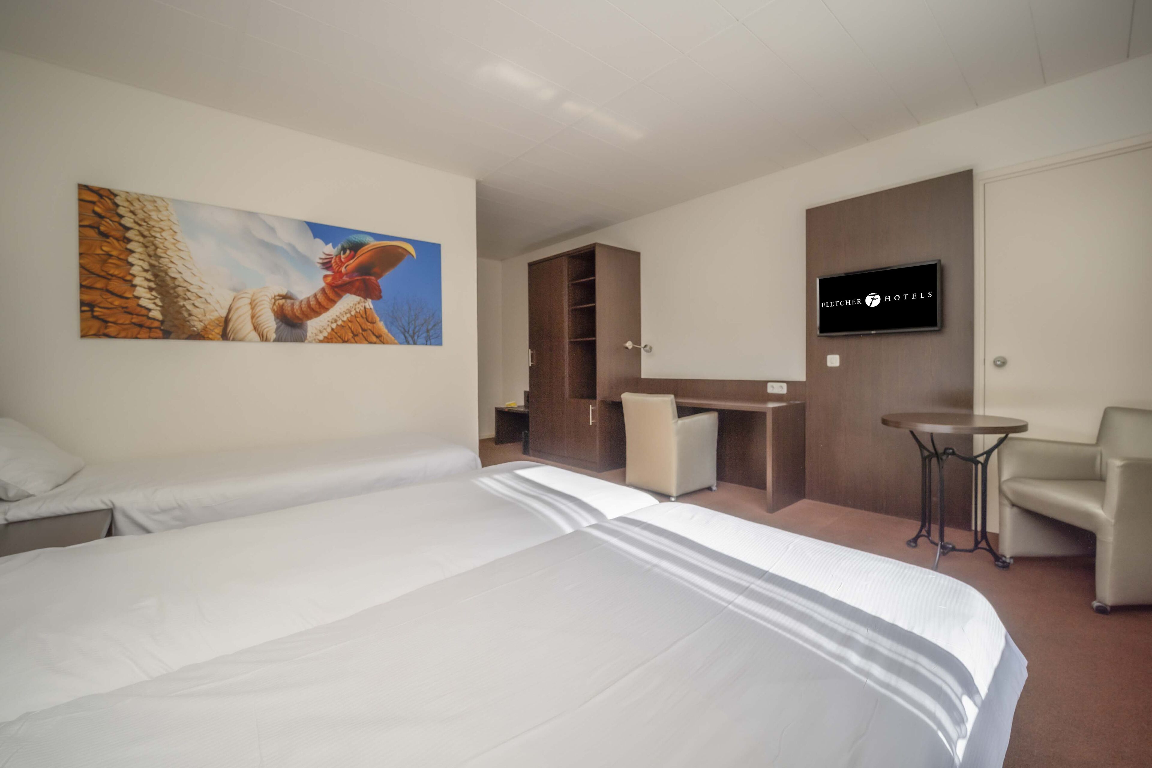 A hotel room with a large bed, a desk, a chair, a television, and a painting on the wall.
