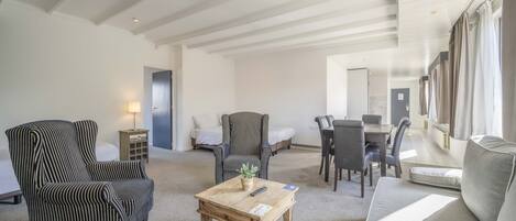 A spacious living area with striped armchairs, a wooden coffee table, and a sofa.