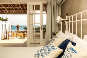 A bedroom with a bed, a nightstand, a lamp, and a view of the sea. - Pousada Baia Bonita (Búzios)