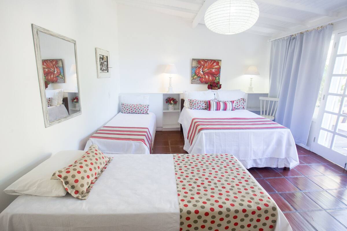 A hotel room with two single beds, a large mirror, and artwork on the walls.